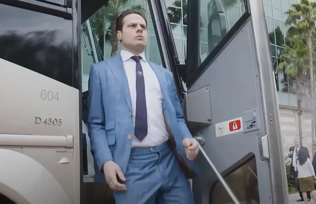 A man in a light blue suit steps off a bus, looking focused as he descends onto the street.