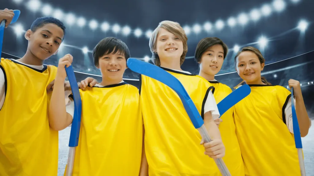 Group of young hockey players in yellow jerseys holding sticks in an arena.